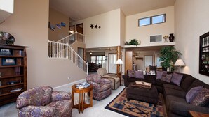 A spacious living room with a staircase, a coffee table, and a sofa. - Dalton Ranch Townhome on 11th Fairway & Waterway - A/C - Unbeatable Views (Durango)
