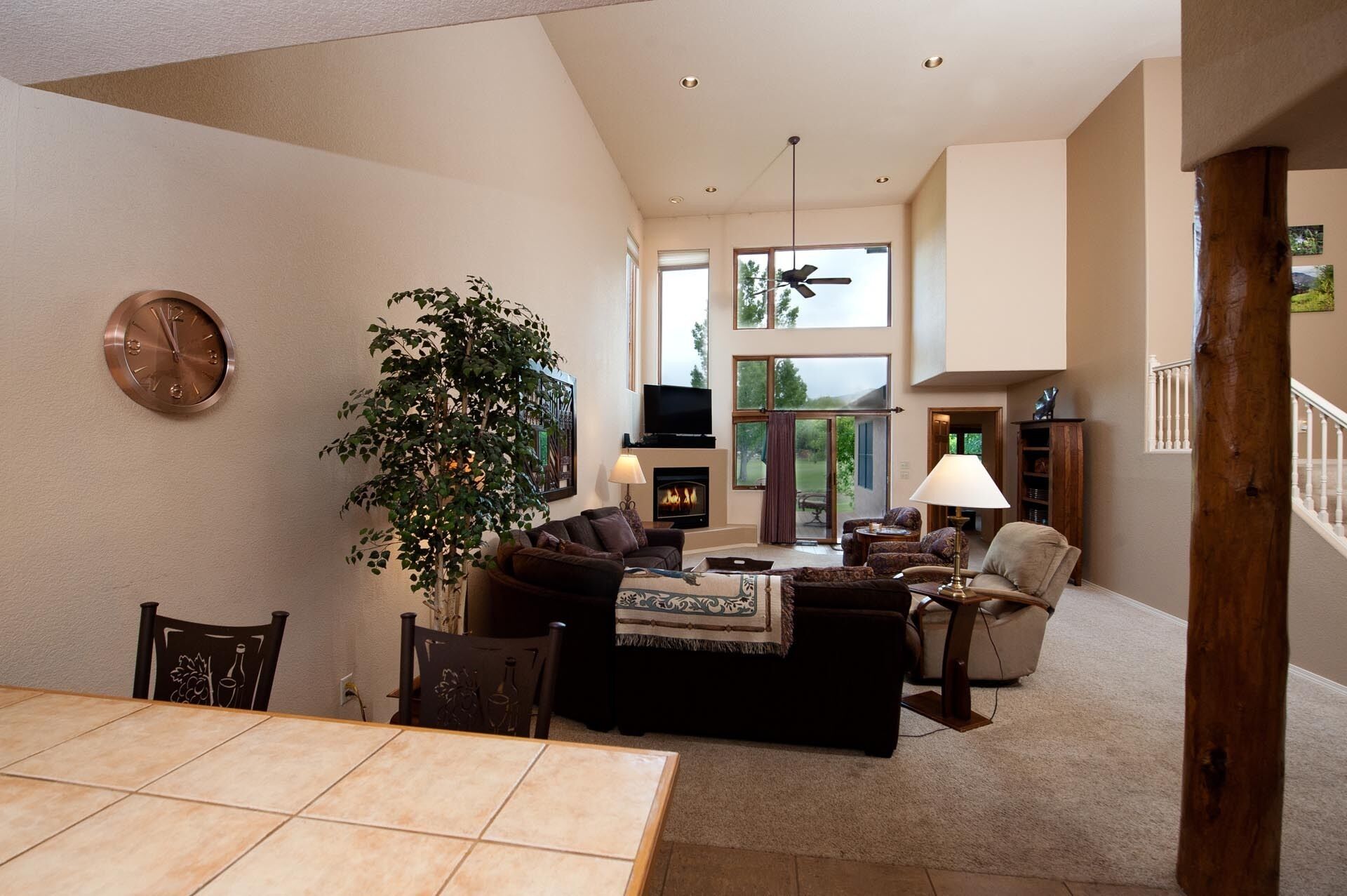 A spacious living room with a fireplace, comfortable seating, and a large window offering a view of the outdoors.