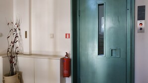 A door with a fire extinguisher mounted on the wall beside it. - Thalia Apartment Kalamata (Kalamata)