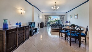 Una sala de estar moderna con televisor, sofá, mesa de comedor y sillas.