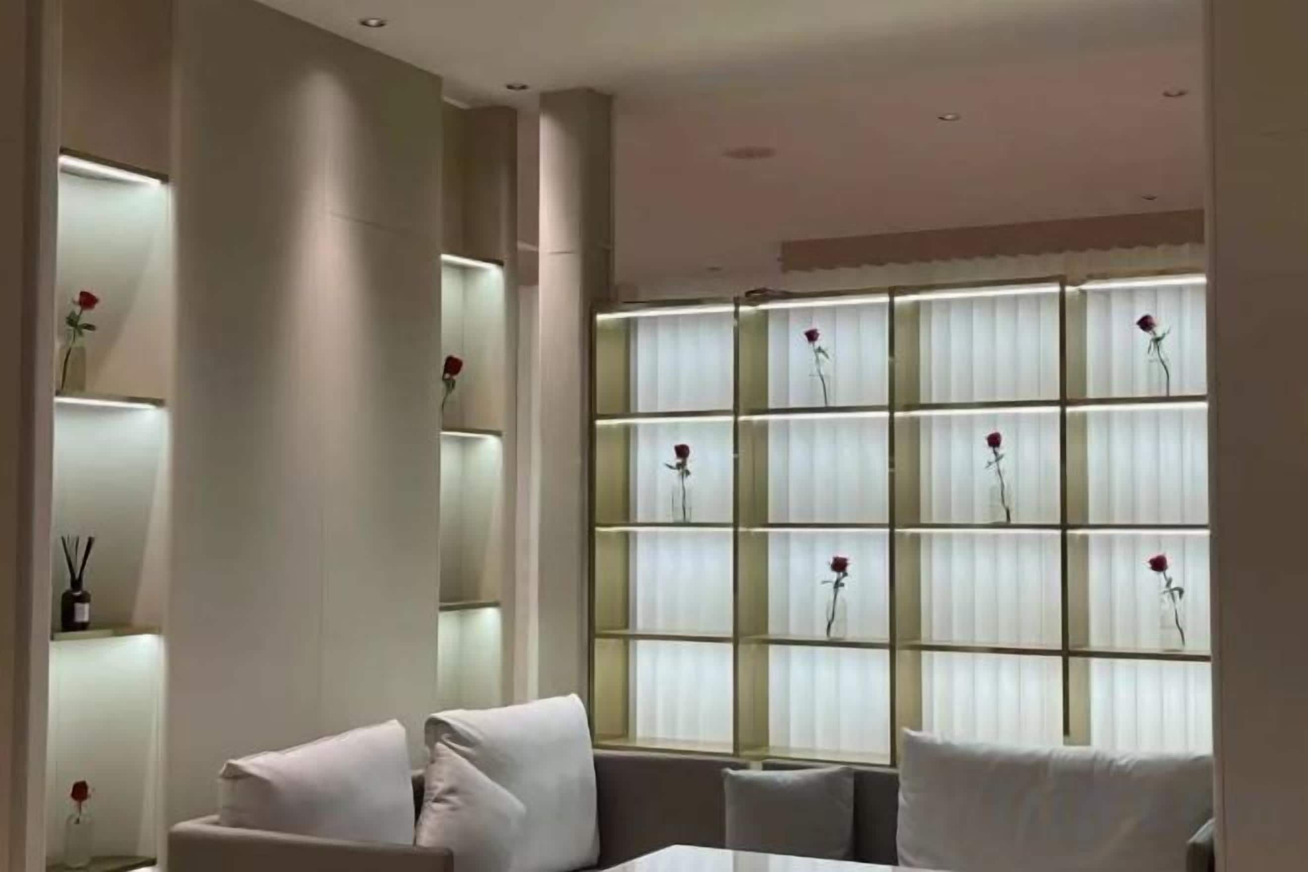 Un intérieur moderne comprenant un coin salon, une grande fenêtre ornée de motifs floraux et une étagère avec des vases.