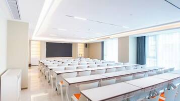 A classroom with rows of desks, a projector screen, and a large window.