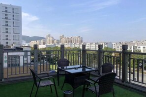 Ein Balkon mit Tisch und Stühlen, Blick auf eine Stadtlandschaft und ein Gebäude im Hintergrund.