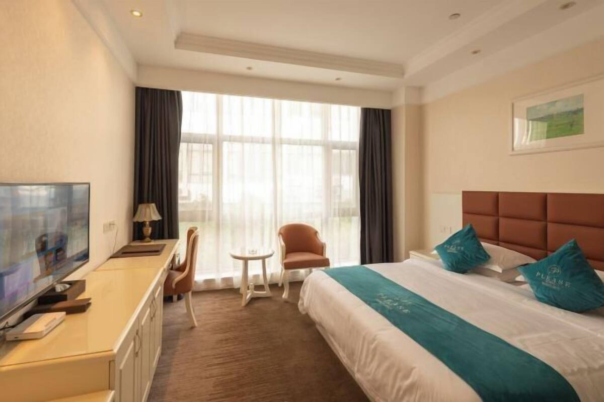 A hotel room with a bed, a TV, a desk, and a chair.