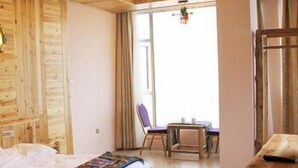 A wooden room with a bed, a table, and a chair. - Panorama House Hotel (Guilin)