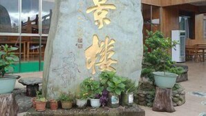 A stone monument with gold lettering in an outdoor area with potted plants and a building in the background. - Panorama House Hotel (Guilin)