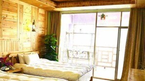 A wooden room with two beds, a table, and a large window with curtains. - Panorama House Hotel (Guilin)
