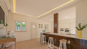 A modern kitchen with a central island, bar stools, and built-in appliances. - Casa da Praia - Fantastic villa located in a privileged area just few minutes to Galé beach and large pool and garden (Galé)