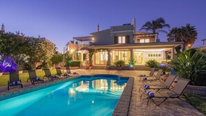 A modern two-story house with a swimming pool, lounge chairs, and a well-lit patio area. - Casa da Praia - Fantastic villa located in a privileged area just few minutes to Galé beach and large pool and garden (Galé)