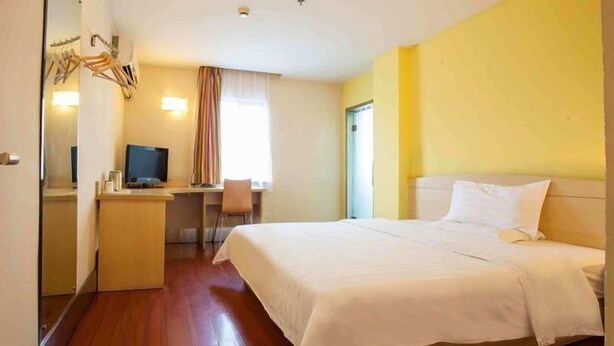 A hotel room with a bed, a desk with a computer, and a mirror. - 7 Days Inn Suqian Fazhan Avenue (Suqian)