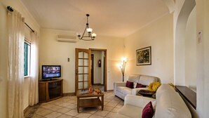 Una sala de estar con televisor, sofá, mesa de centro y un cuadro en la pared.