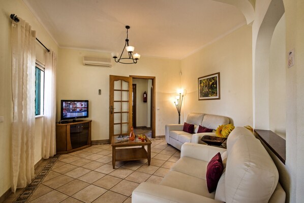 A living room with a television, a sofa, a coffee table, and a painting on the wall.