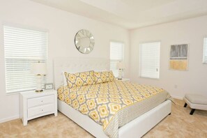 Un dormitorio con cama, mesitas de noche, un reloj de pared y una ventana con persianas.
