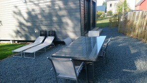 An outdoor patio with a rectangular table and four chairs, surrounded by gravel. - Gîte "l'aiguille creuse (Criquebeuf-en-Caux)