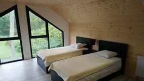 A bedroom with two beds, large windows, and a sloped ceiling. - Gîte "l'aiguille creuse (Criquebeuf-en-Caux)