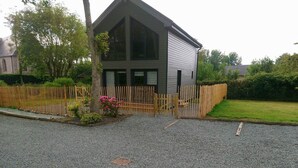 A two-story building with a gabled roof, a wooden fence, and a gravel driveway. - Gîte "l'aiguille creuse (Criquebeuf-en-Caux)