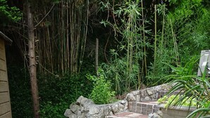 A stone pathway leading to a brick structure surrounded by lush greenery and bamboo. - LUVA D'azur LE RIOU in the heart of the Grasse region (Le Bar-sur-Loup)