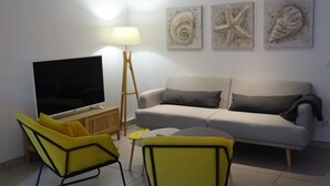 A living room with a sofa, two yellow chairs, a coffee table, a floor lamp, and a TV. - LUVA D'azur LE RIOU in the heart of the Grasse region (Le Bar-sur-Loup)