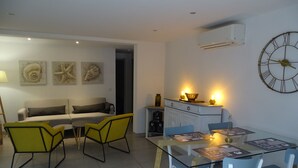 A modern living room with a sofa, yellow chairs, a glass dining table, and a wall clock. - LUVA D'azur LE RIOU in the heart of the Grasse region (Le Bar-sur-Loup)