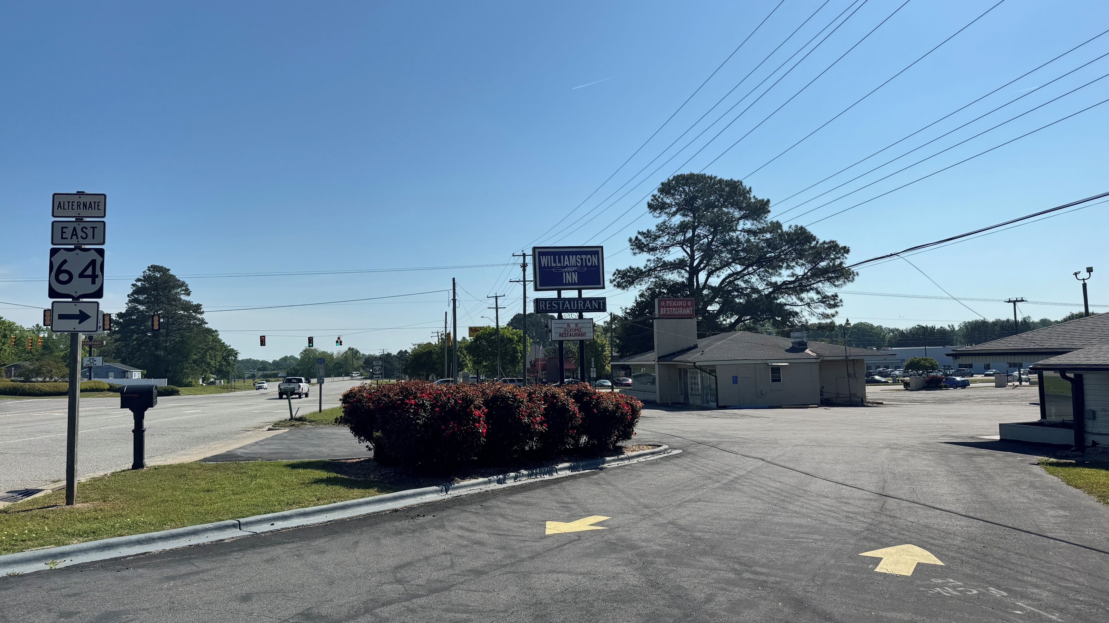 A road intersection with directional signs for Route 64 East and a Williamston Inn sign.