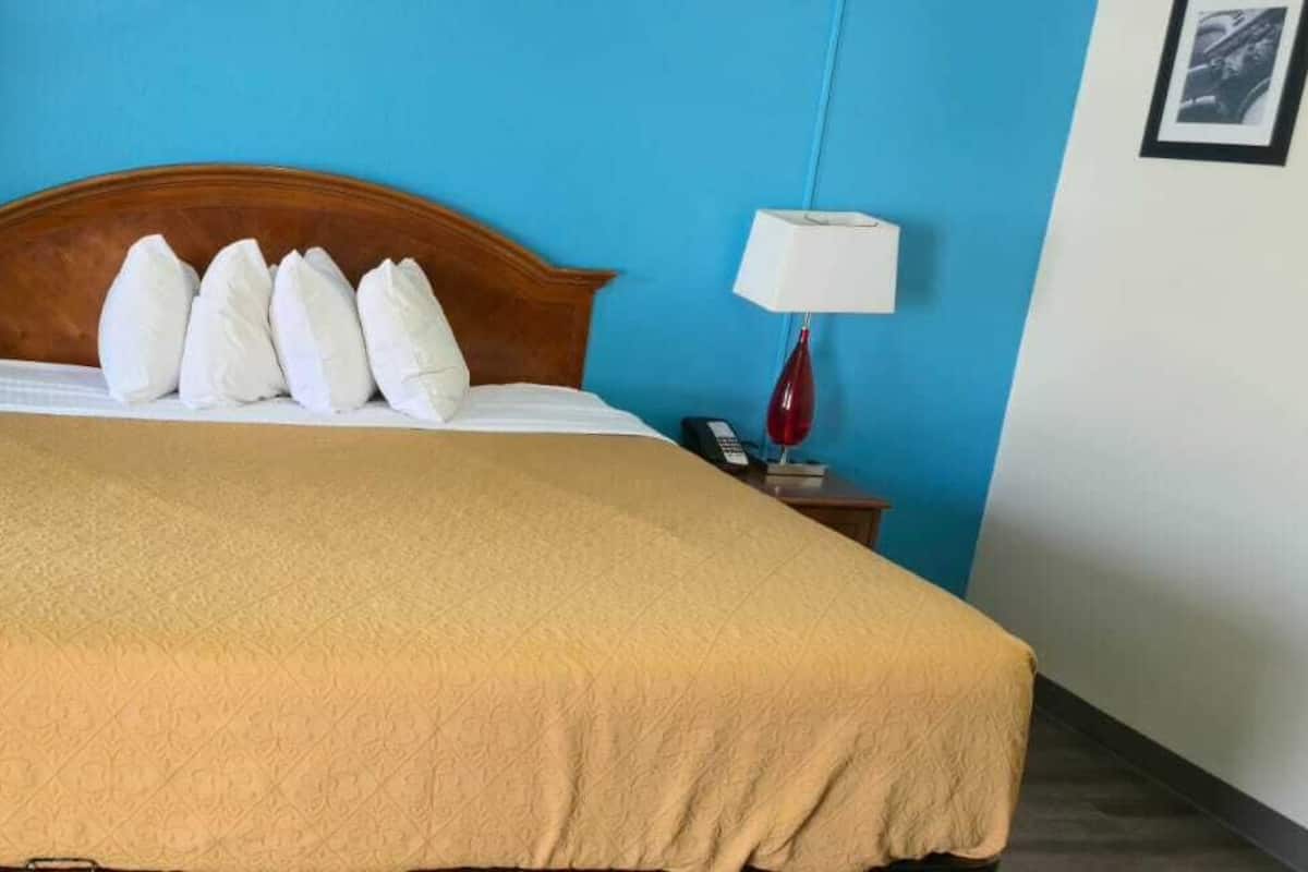 Une chambre d’hôtel avec un grand lit, deux tables de chevet, une tête de lit en bois et un mur bleu.