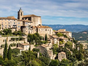 A historic town with stone buildings, a prominent tower, and lush greenery.