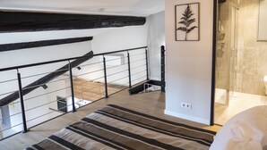 Un interior moderno con una escalera de madera, una alfombra a rayas y una planta enmarcada en la pared.