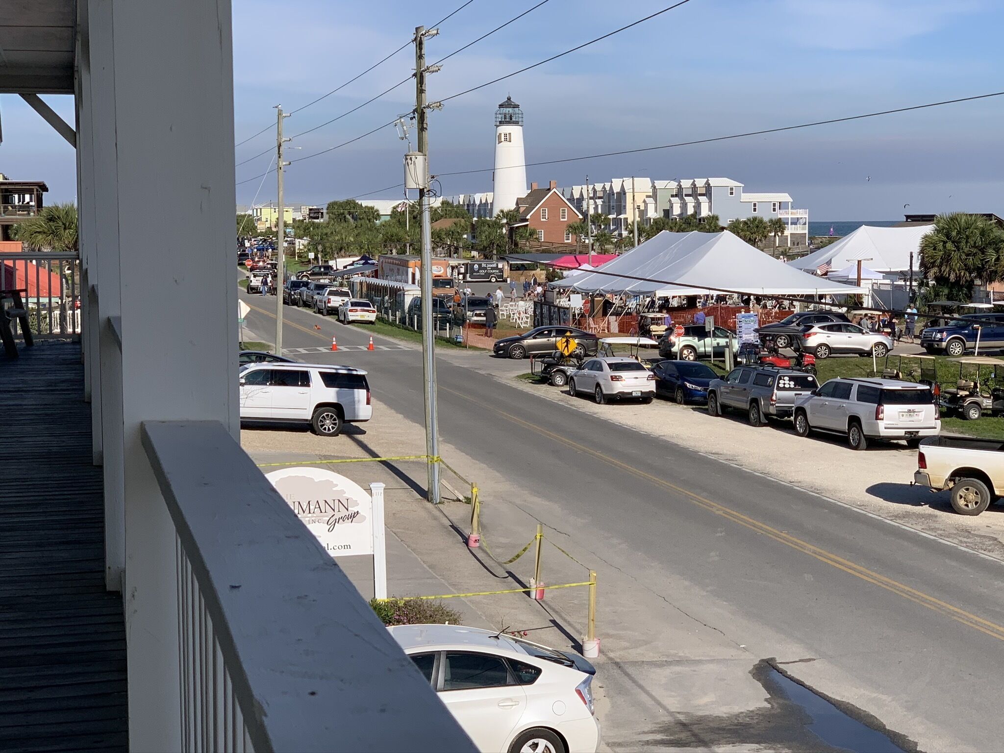 A street view with a white building, a lighthouse, and a golf course sign.
