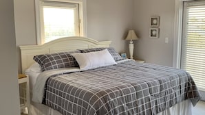 A bedroom with a bed, a nightstand, a lamp, and a window with blinds.