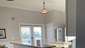 A kitchen with a wooden countertop, white bar stools, and a window with blinds.