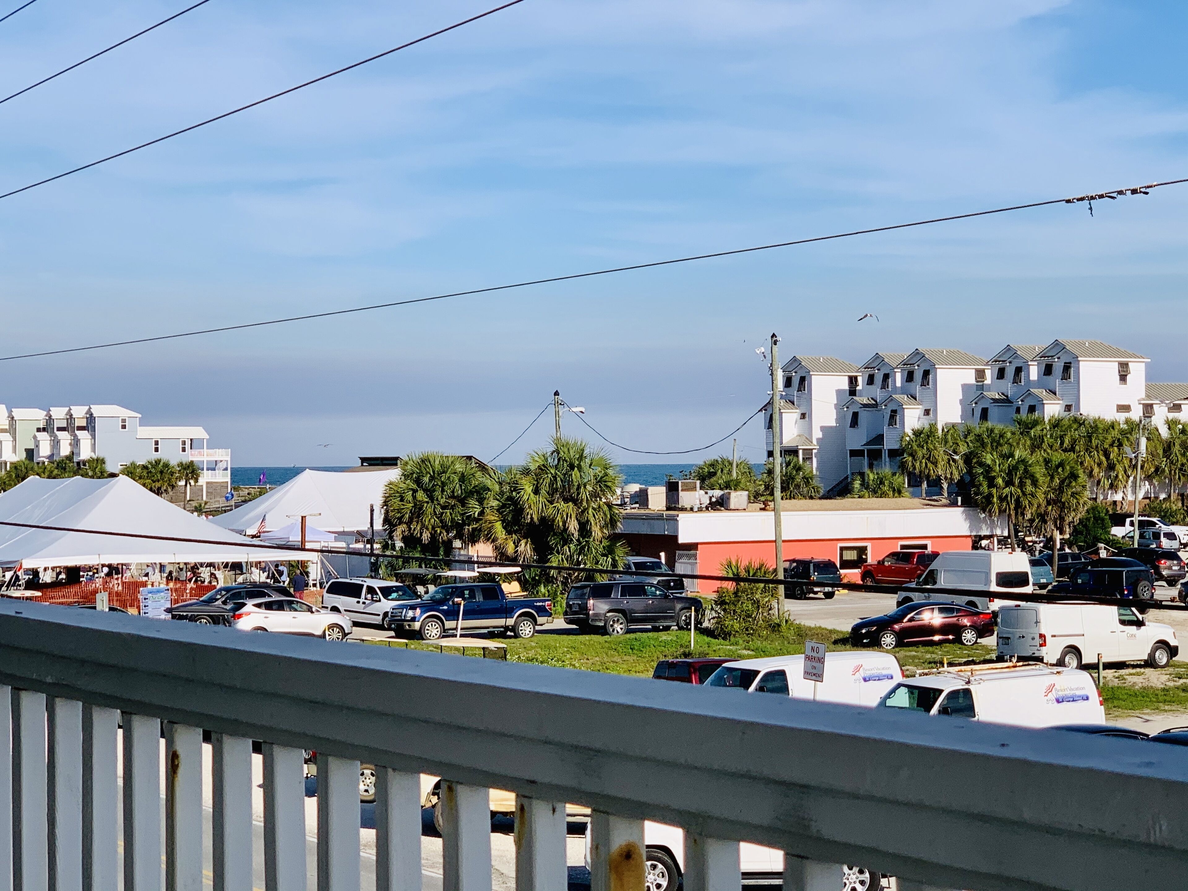 A coastal town with buildings, parked cars, and a clear sky.