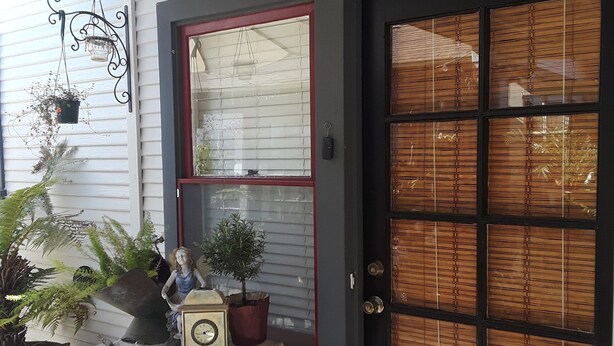 A front door labeled "French Quarter" with a decorative sign, a window with blinds, and a small table with potted plants and a clock.
