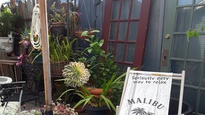 A garden area with various potted plants and a signboard advertising 'Malibu'.