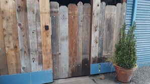 A wooden fence with a blue trim and a potted plant beside it.