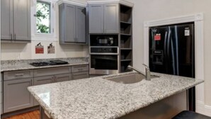 A modern kitchen with granite countertops, grey cabinets, a built-in oven, and a stainless steel refrigerator. - TOBIN HILL OASIS - PRIVATE POOL HOUSE 3BD/2.5BA, SCREENED IN PORCH, FULL KITCHEN (San Antonio)