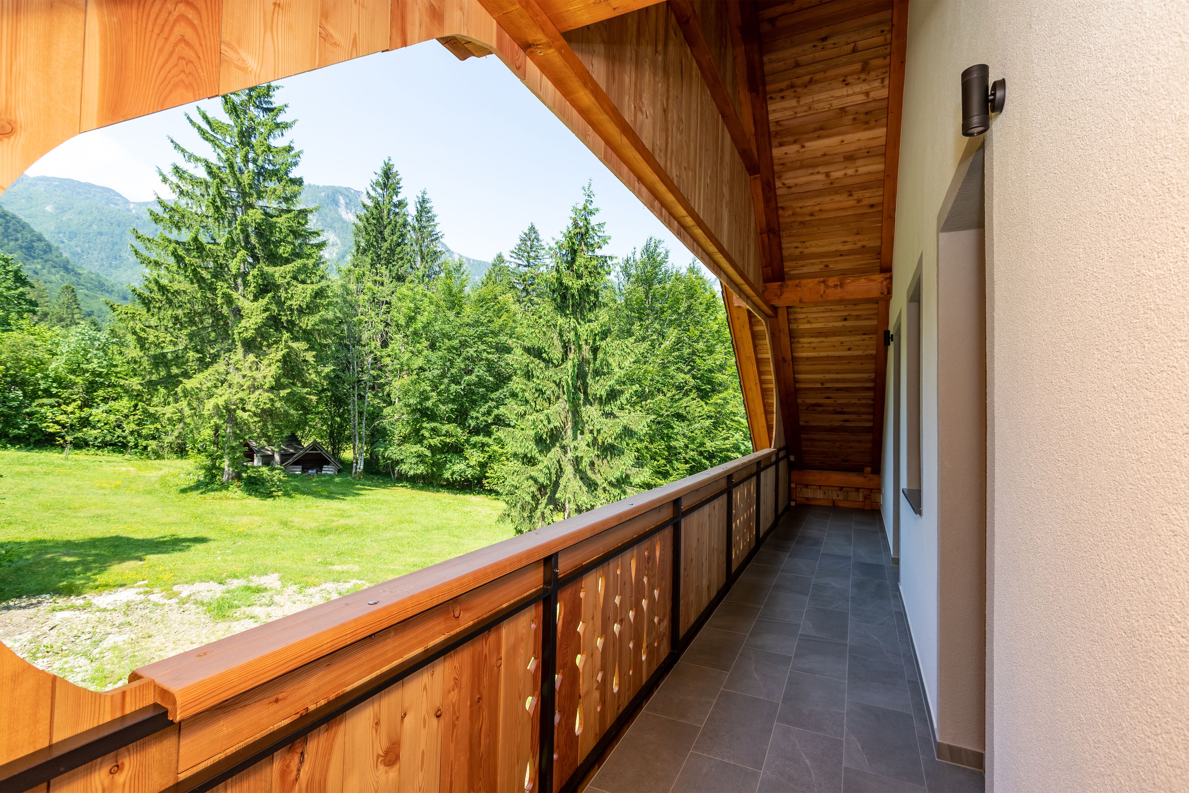 Un balcón de madera con vistas a un paisaje verde y montañas.