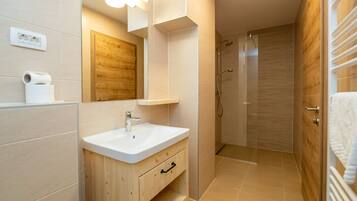 A modern bathroom with a wooden vanity, a large mirror, and a shower area.