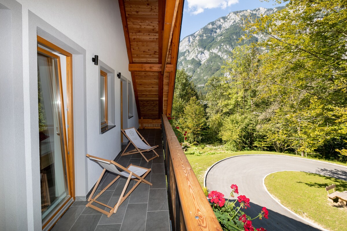 A balcony with wooden railings, a glass door, and two folding chairs.