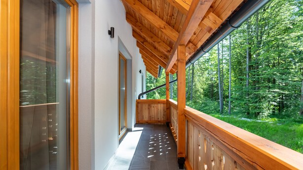 Ein Holzbalkon mit Blick auf einen Wald.