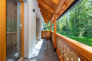 Un balcón de madera con vista a un bosque.