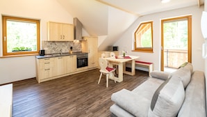 Eine moderne Küche mit Holzschränken, einem Esstisch und einem grauen Sofa.