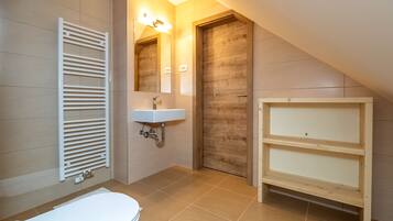 A bathroom with a white toilet, a sink with a mirror, a wooden door, and a white radiator.