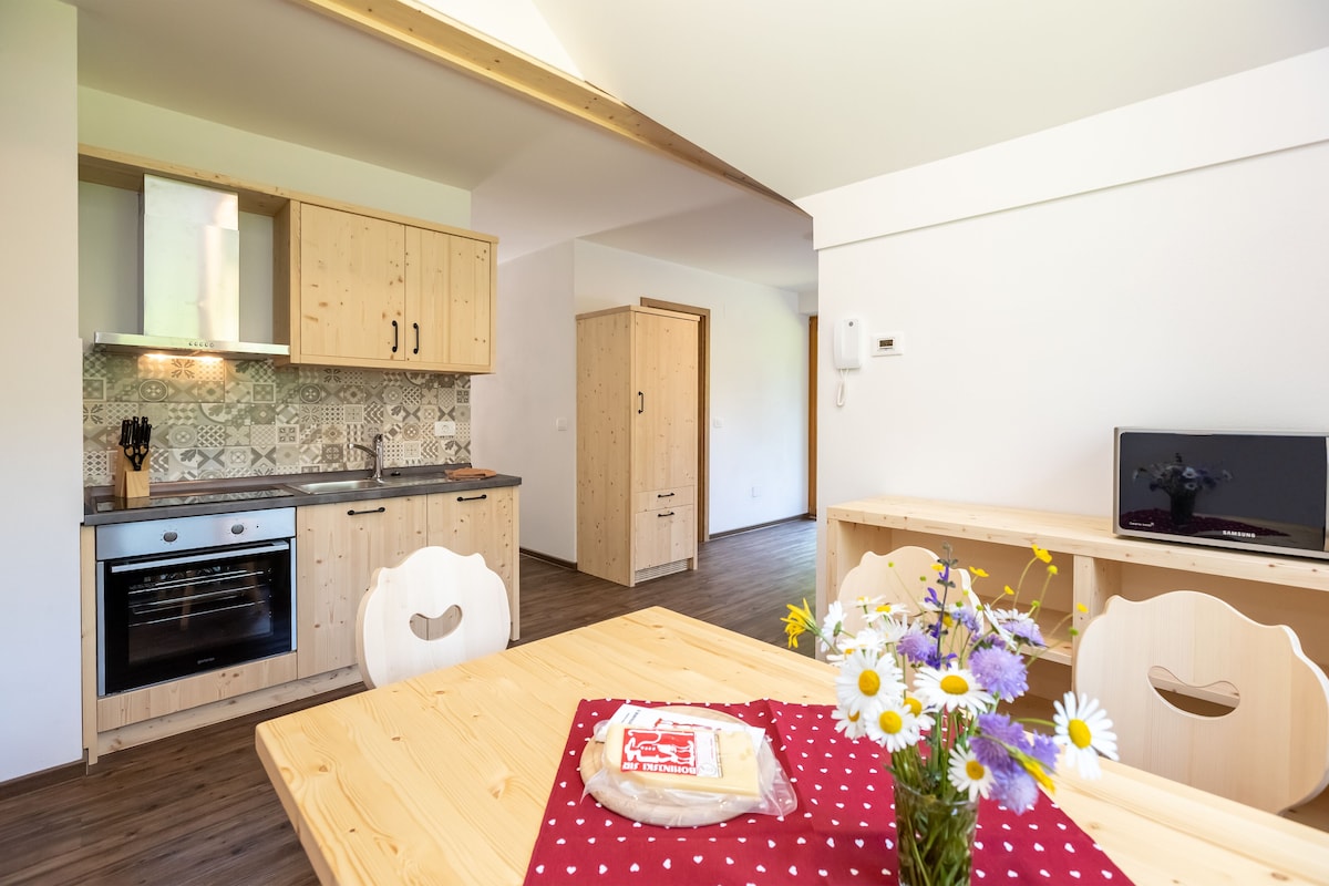 A kitchen with wooden cabinets, a built-in oven, and a dining area with a table set for two.