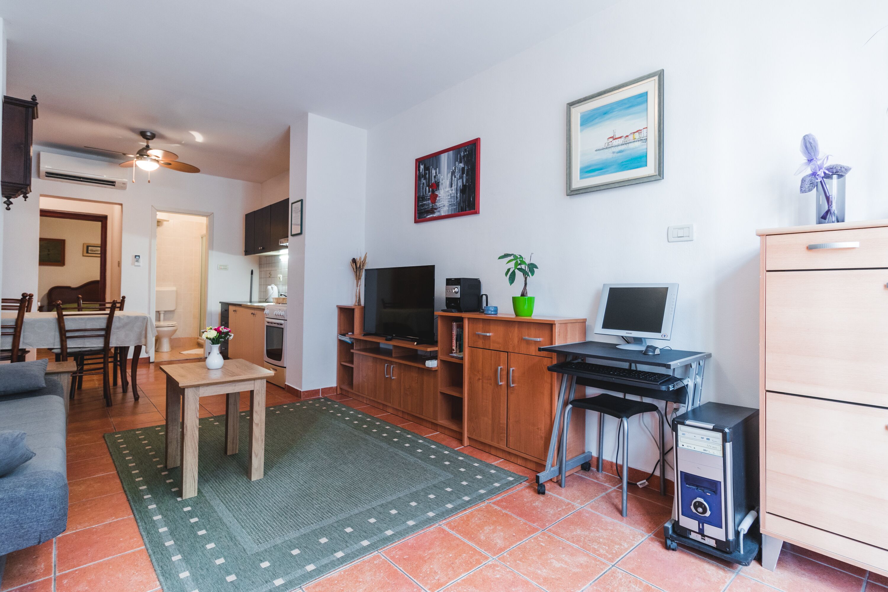 Een ruimtelijke woonruimte met een eethoek, kitchenette en een computerbureau.