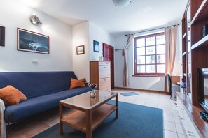 A modern living room with a sofa, coffee table, and a television. - Apartments Pri Mari (Piran)