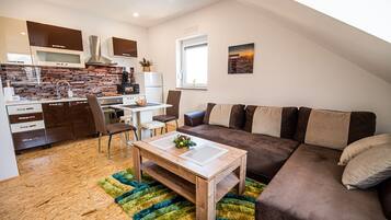 Une cuisine moderne dotée d’un four et d’un micro-ondes encastrés, un coin repas avec une table et des chaises, et un espace de vie avec un canapé et une table basse.