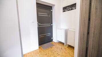 A hallway with a black door, white cabinets, and a radiator.