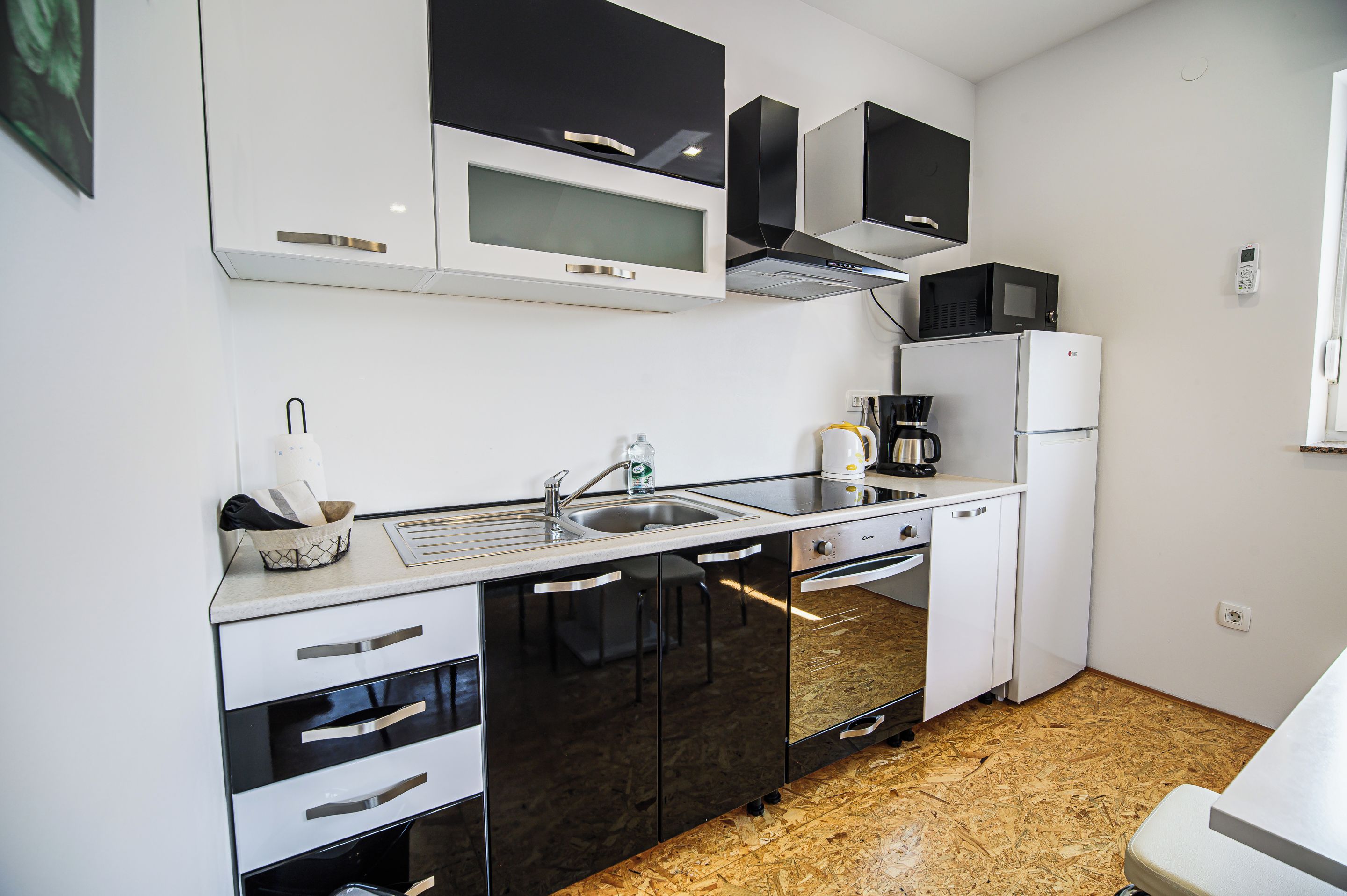 Una cucina compatta con lavandino, fornelli, forno a microonde e frigorifero.