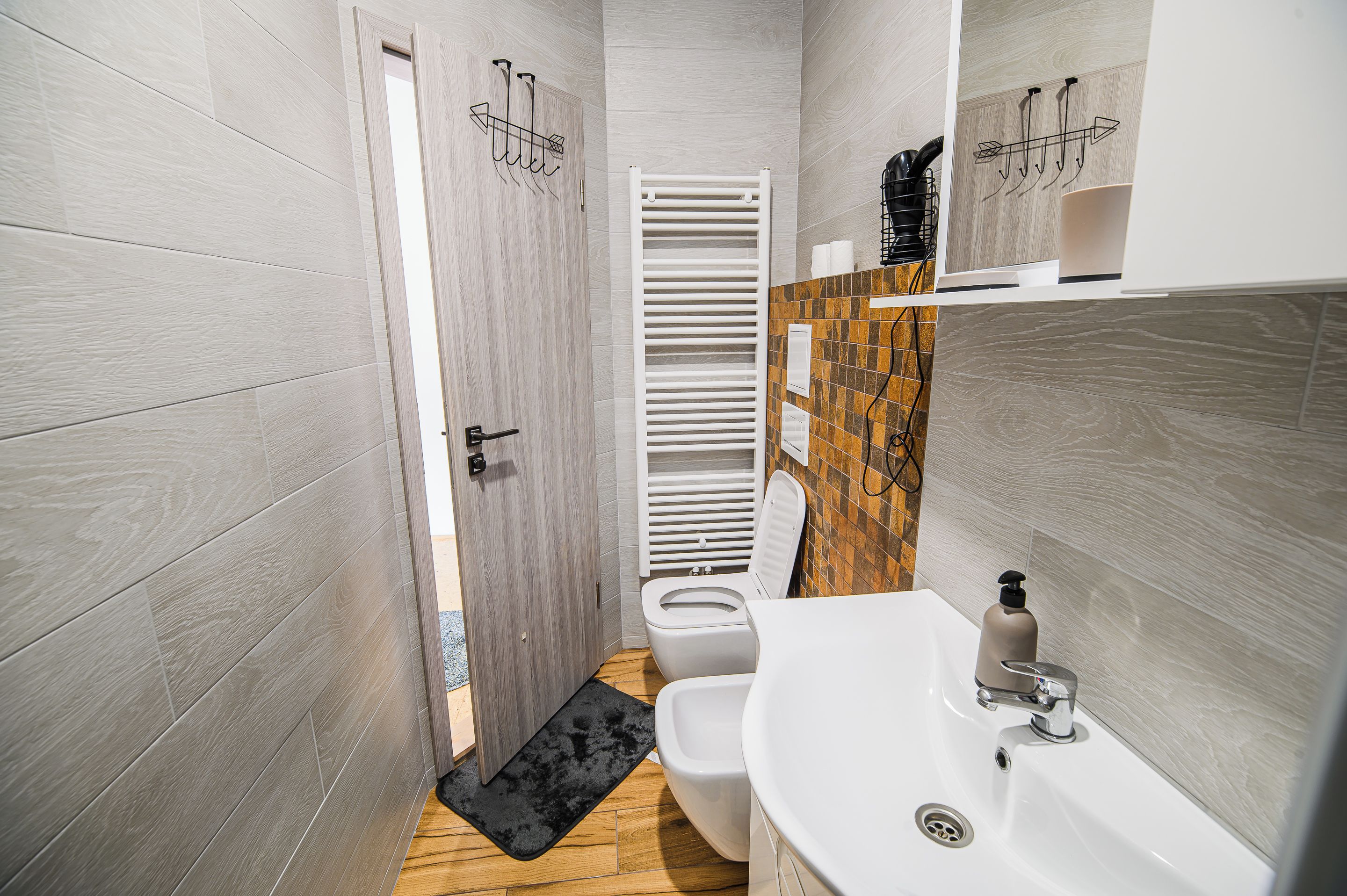 A modern bathroom with a toilet, bidet, and a white sink with a mirror.