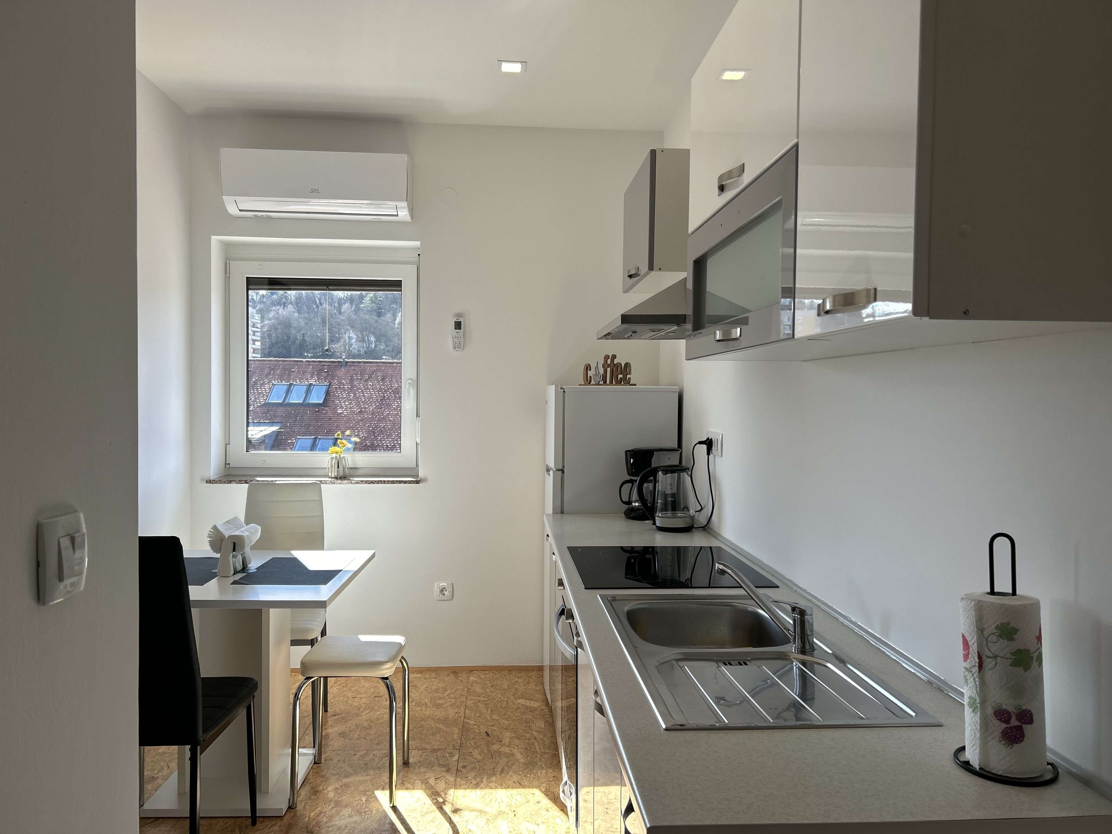A modern kitchen with a window, a coffee machine, and a sink.